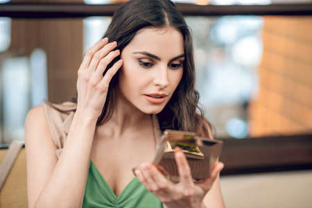 Beautiful young woman looking excited and checking her mak upの写真素材