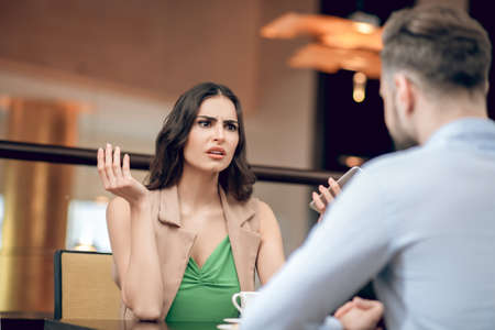 Young woman talking to a man and looking disappointedの写真素材