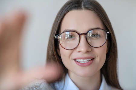 Headshot of long-haired woman in eyeglasses looking positive
