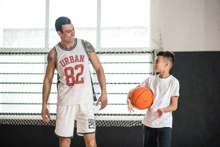 Coach in white sportswear teaching the boy playing basketballの写真素材