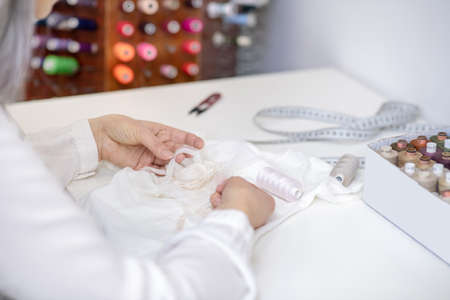 Woman hands sewing decor to white clothesの写真素材