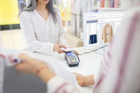 Payment, contactless. Woman in white blouse making payment for order using smartphone and seller...