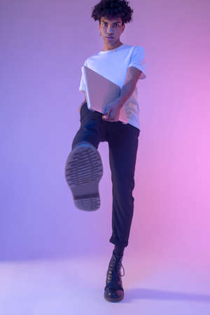 African american young guy in white tshirt with a laptop making a step