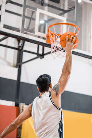 Sportman throwing a ball into the basketの写真素材
