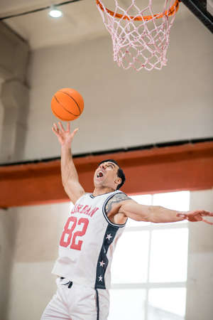 Sportman throwing a ball into the basketの写真素材