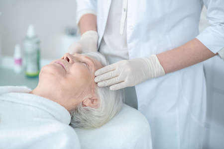 Mature woman enjoying face massage and looking relaxed