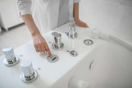 Specialist in spa salon getting the bath for hydromassage ready