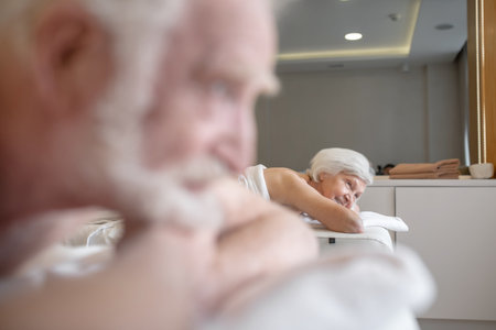 Gray-haired senior man lying on a couch and waiting for back massageの写真素材