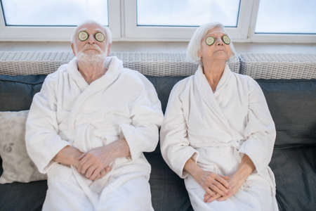 Senior couple in white robes enjoying spa procedures and having funの写真素材