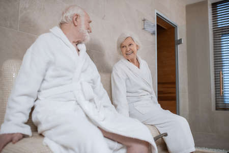 Senior couple in white robes having procedures for legs in spa salonの写真素材