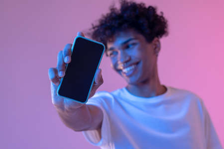 Headshot of curly-haired smiling guy with a smartphone