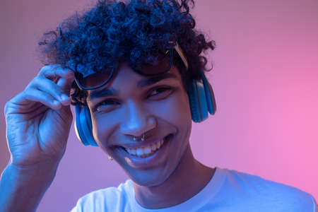 Dark-skinned guy in headphones smiling nicely and looking happy