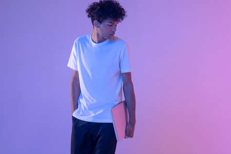 Curly-haired young guy in white tshirt with a laptop