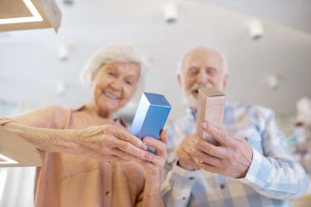 Gray-haired couple choosing perfumes and looking excitedの写真素材