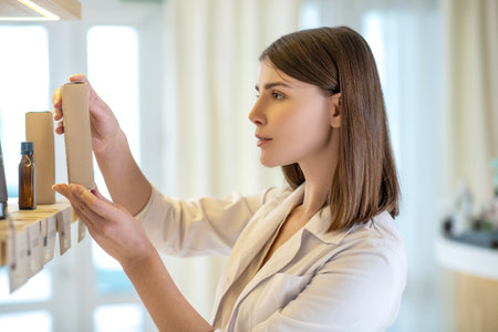 Pretty shop assistant examining new products and looking involvedの写真素材