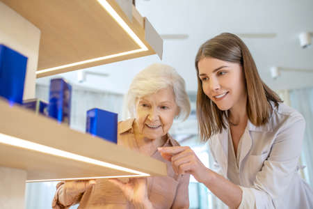 Young dark-haired shop assistant helping a customer to choose a new perfumeの写真素材