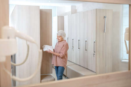 Gray-haired mature woman in a changing room in spa centerの写真素材