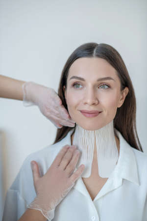 Cute young woman visiting beauty center and having taping procedureの写真素材