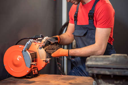 Male hands holding part near grinding machine