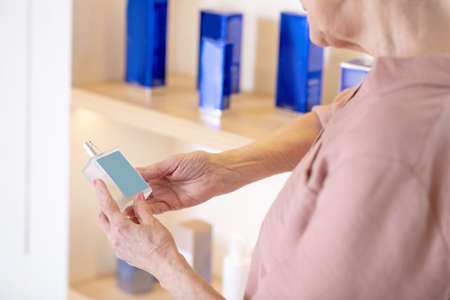 Mature short-haired woman choosing perfumes in a boutiqueの写真素材