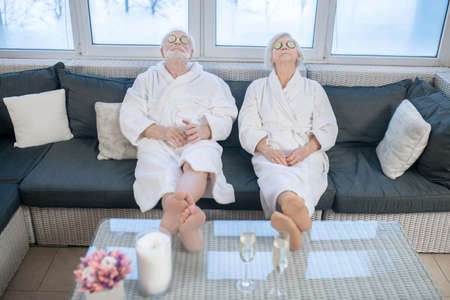 Mature couple in white robes relaxing in a spa center and feeling comfortableの写真素材