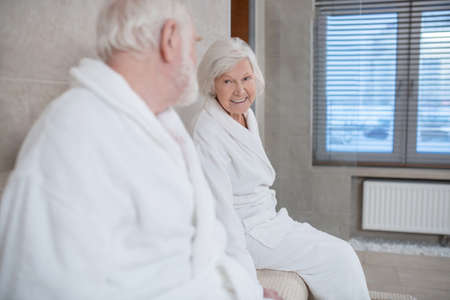 Gray-haired man in a white robe with a laptopの写真素材