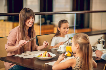 Happy family sitting at the table in the restaurantの写真素材