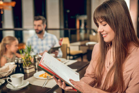 Young woman holding a menu and choosing what to orderの写真素材