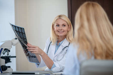 Smiling doctor with MRT scan and patient backの写真素材