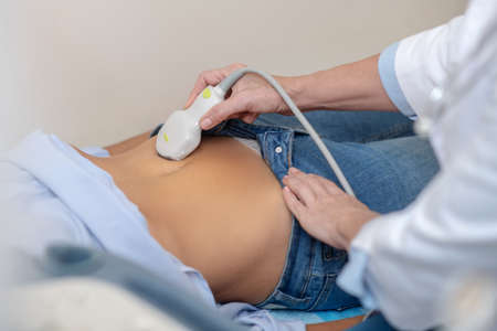 Patient abdomen and doctor hands with ultrasound sensorの写真素材