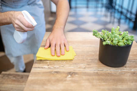 Male hands wiping table surface in cafe