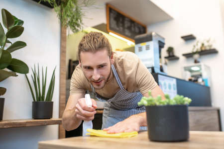 Attentive man wiping the surface with concentration