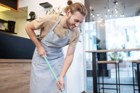 Joyful man with mop near bar counterの写真素材