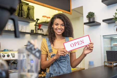 Smiling girl inviting visitors to opening cafe