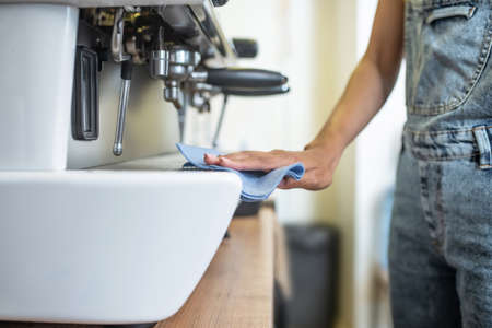 Womans hand with napkin sliding on coffeemakerの写真素材