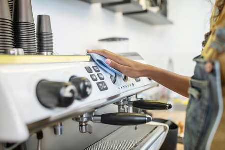 Womans hand wiping panel of coffee machineの写真素材