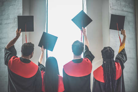 A group of graduates holding their mortarboards in the airの写真素材