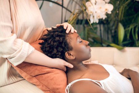 Young healer working woith a dark-skinned patient in ayurvedic salonの写真素材