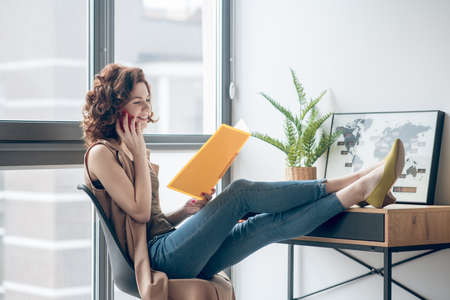 Young woman working on a project and discussing it with a colleague on the phoneの写真素材