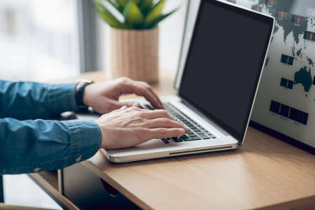 Close up picture of mans hands typing on a laptop