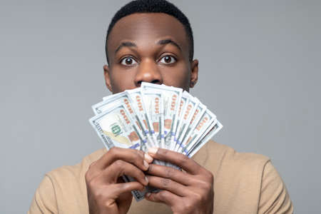 Man holding banknotes near his face
