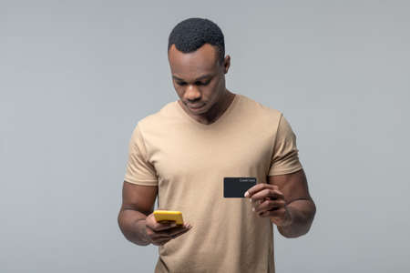 Man with credit card looking into smartphone