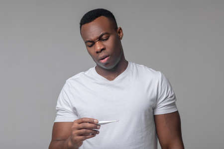 Upset african american with thermometer in hand