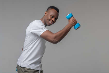 Attractive joyful man with dumbbells doing sports
