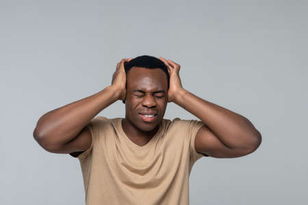Man with closed eyes touching hands to head