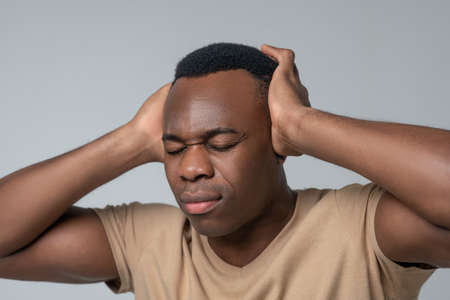 Close-up photo of man covering ears with hands