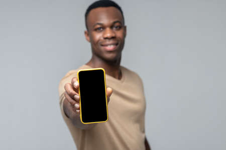Man showing smartphone screen in hand outstretched forward