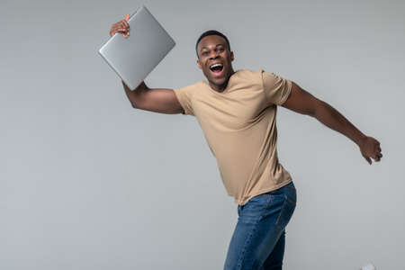 Cheerful man with laptop waving handsの写真素材