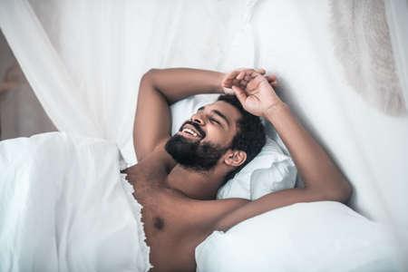 Smiling man with closed eyes in bedの写真素材