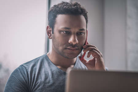 Young businessman sitting at the table in the office and talking on the phone